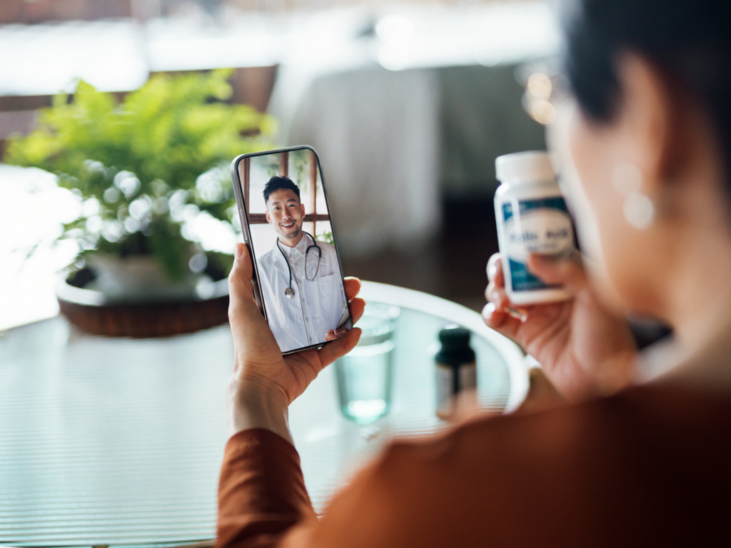 Senior Asian woman having a virtual appointment with doctor online, consulting her prescription and choice of medication on smartphone at home. Telemedicine, elderly and healthcare concept